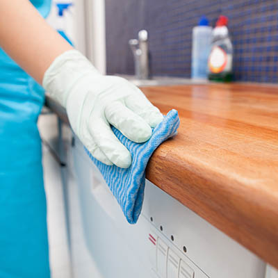 Hand wearing a white glove cleaning a benchtop.